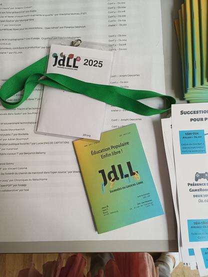 Un programme bleu vert jaune en format poche et un badge intervenant avec un tour de cou vert.