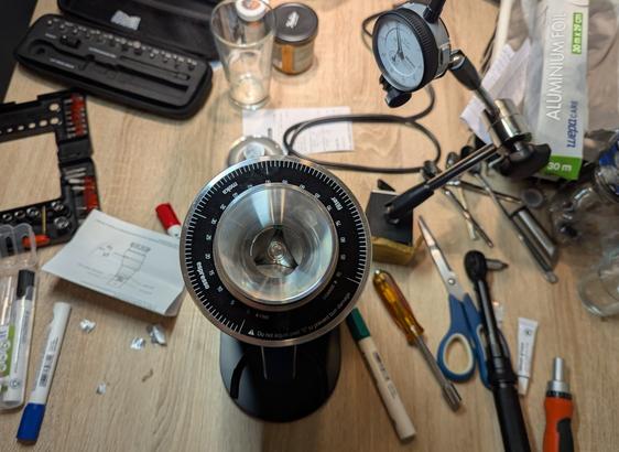 Messy table with the grinder in the center , tourq wrench, markers, screwdrivers, dual indicator and aluminum foil scattered around.