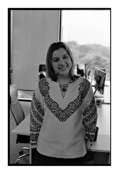 A smiling woman wearing a traditional Ukrainian embroidered shirt (vyshyvanka) stands in an office on Vyshyvanka Day. Shot on Ilford HP5+ film with a Nikon FM