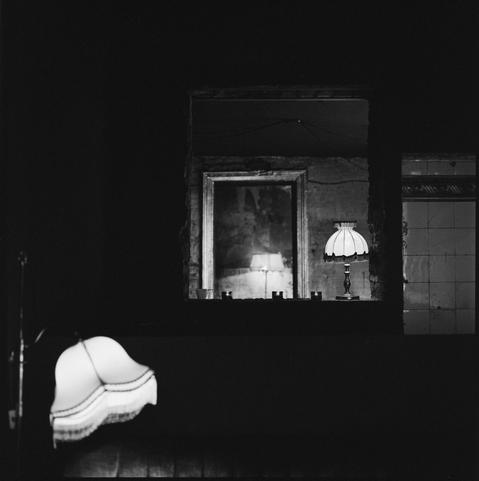 black and white photograph of several old fashioned lamp shades in a very gloom looking bar.