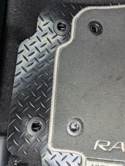 Edge view of some car foot well mats showing that the fixing points on the new ones are ninety degrees out of alignment