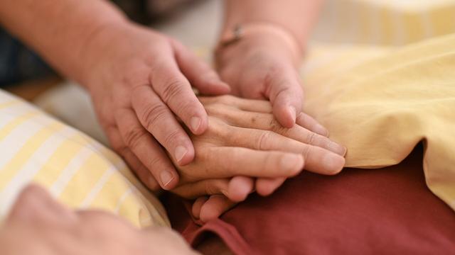 Eine Hospizmitarbeiterin hält die Hand eines todkranken Menschen © picture alliance/dpa Foto: Felix Kästle