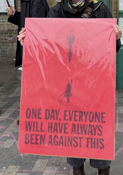 Red placard held by a protester. It says:

ONE DAY. EVERYONE
WILL HAVE ALWAYS
BEEN AGAINST THIS