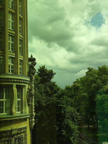 Foto: Deutsche Nationalbilbiothek Leipzig, ein Stück Fassade Altgebäude, Bäume, Himmel mit Regenwolken