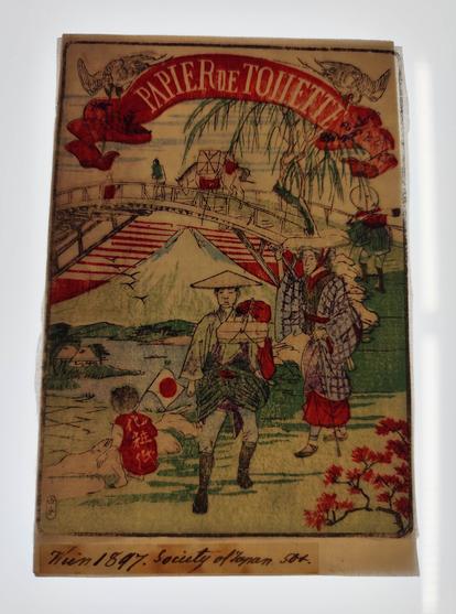 Foto: Handgeschöpftes Toilettenpapier aus Japan: "Titelblatt" mit der Aufschritft "Papier de Toilette", koloriertes Bild mit Personen mit japanischer Kleidung. Darunter handschriftlicher Vermerk: "Wien 1897. Society of Japan, 500"