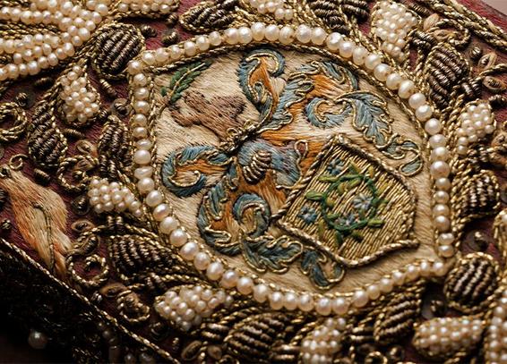 A closeup of the binding showing a ring of pearls surrounding a coat of arms.