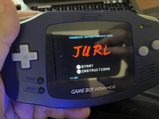 An individual is holding a Game Boy Advance, displaying a game screen titled "JURL" with options to "START" and "INSTRUCTIONS." The background indicates it's a game from Tonsodo Entertainment, dated 2024.