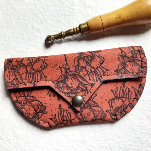 Pochette en liège de couleur brique, imprimée et cousue à la main. Le motif sont des fleurs de fushia imprimées à répétition.