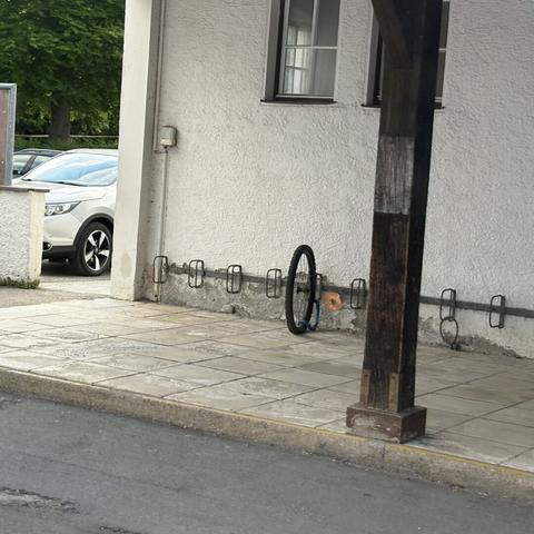 A lonely bike tire, securely locked to a bike rack at a train station. The rest of the bike is missing, though.