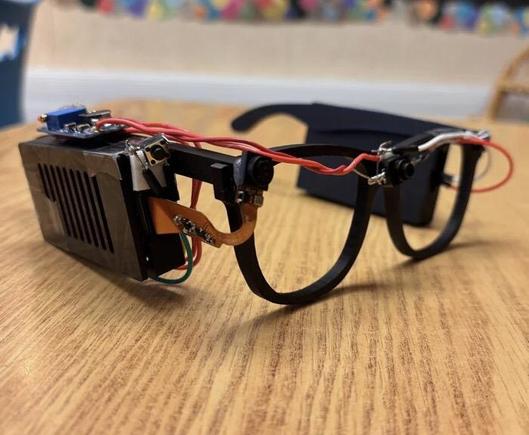 [ImageSource: Akhil Nagori]

Yes, we’re talking about real-time text-to-audio transcription, built into a head-worn format. The hardware is pretty straightforward: a Raspberry Pi Zero 2W runs off a battery and is outfitted with the usual first-party camera. The camera is mounted on a set of eyeglass frames so that it points at whatever the wearer might be “looking” at.

At the push of a button, the camera captures an image, and then passes it to an API which does the optical character recognition. The text can then be passed to a speech synthesizer so it can be read aloud to the wearer.