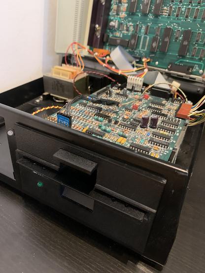An opened Commodore 8050 floppy drive, partially disassembled. Only one drive is installed, and PCBs are visible in the background