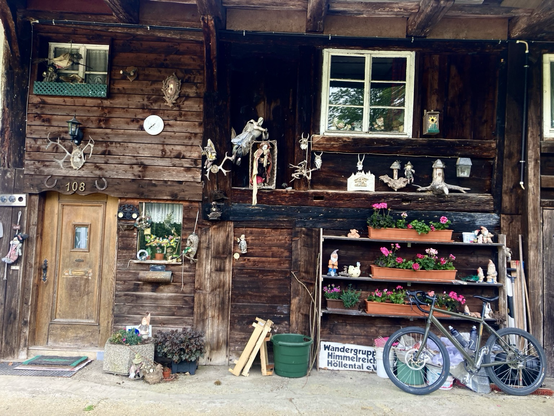 Fahrrad vor einem reich verzierten Scharzwaldhaus. Unten steht ein Schild Wandergruppe Hinmelreich Höllental“