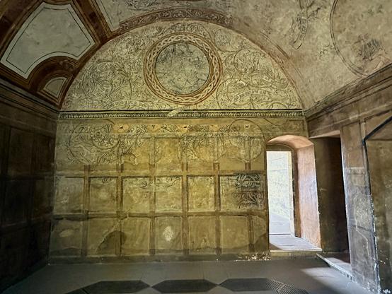 Kinneil House near Bo’ness. The image shows the interior of a room with an arched ceiling and doors on both walls meeting in the lower right of the frame. The interior surfaces of the room are all highly decorated with painted panels and intricate patterns. The left side of the ceiling carries bolder decorations.