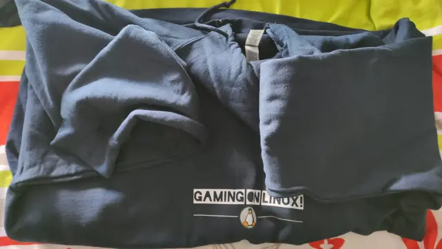 A dark blue hoodie laying on bed, showing Gaming on Linux logo.