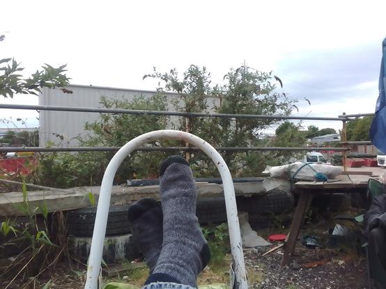 Cloudy sky, pylon, shed, buddlea, the retaining wall of old tyres as permanent formwork. Feet up on a step ladder resting bad knee and newly bad foot (don't ask).