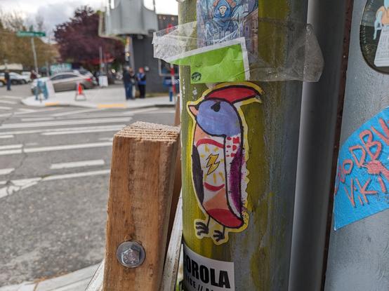 A sticker that looks hand drawn showing an anrgy looking blue bird with a red widardy hat.