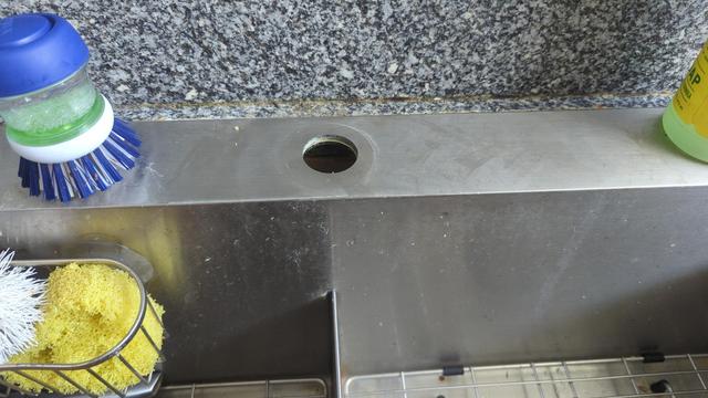 A steel kitchen sink with the faucet removed. There's just a simple hole there now, which is also pretty dirty (I hadn't cleaned it for the new faucet yet).