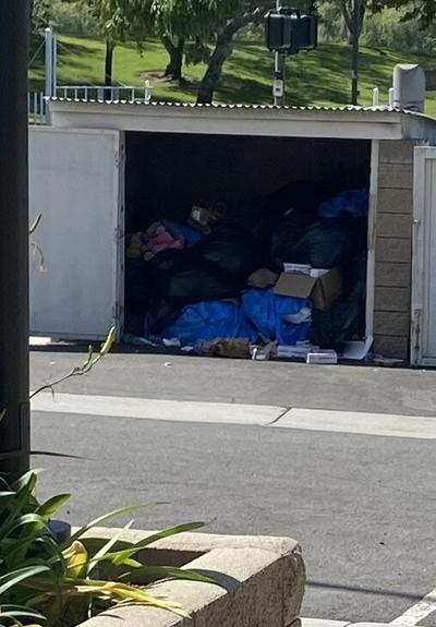 An asphalt driveway with an enclosed trash receptacle area made for commercial sized bins/dumpsters. Doors open to show piles of trash bags without a bin. This is what park privatization looks like. They receive a budget from the city to maintain the area which includes paying for trash bins. This park which remains locked with only the perimeter nature trail open has 3 baseball fields, a soccer field and a football field. The football field used to have two smaller baseball fields which the maintenance company didn’t maintain. The other day it was one small residential bobcat and 7 day laborers with tools watching and waiting. The city has a bulldozer and a certified operator on payroll for this kind of work.
