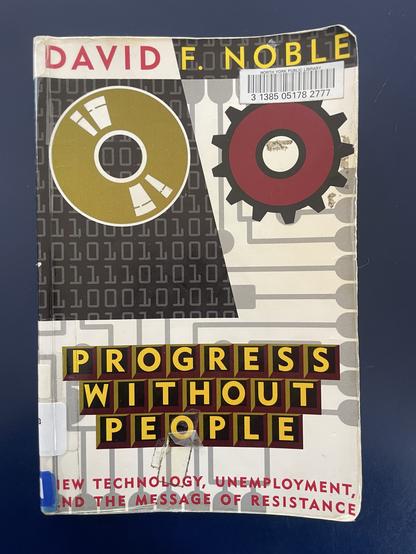 A photo of the cover of a paperback, library copy of the book Progress Without People: New Technology, Unemployment, and the Message of Resistance by David F. Noble.