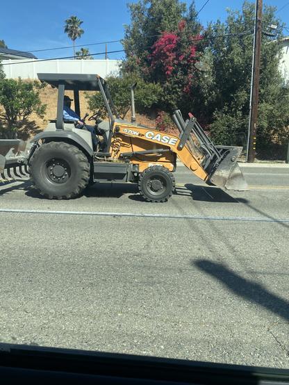 A side view of a city bulldozer on the street.
I spotted this tractor later that day leaving a park with a baseball field attached to a local high school. Appeared to be going back to the city industrial yard. There are people arguing for privatization because they want to sell off the city’s equipment thus not pay insurance on the equipment and not have to pay more for a licensed operator city worker then sell off the property next to the train tacks as site for new “luxury apartments.” I rather have the yard and equipment. But most people who argue for privatization i learned don’t use these facilities any more and what do they care about people whose children aren’t grown—they got theirs and don’t care. Typical “boomers” think—we’re saving money on the budget—to hell with the next generations.