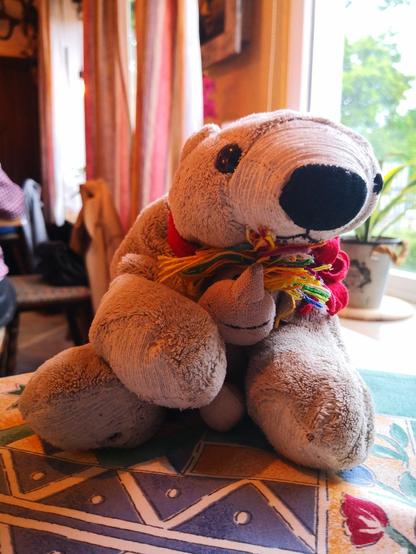 Plüscheisbär Theo knuddelt das kleine Plüscheinhorn Carola zwischen seinen Vordertatzen, währebd beide der Kamera zugewandt sind.