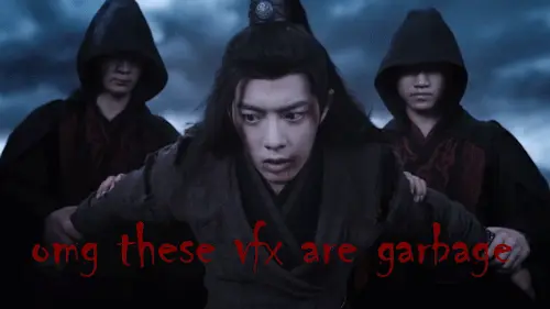 WeiWuxian looking distressed in black as two hooded baddies hold his arms. He is supposed to be flying and about to be thrown to his death, but the background of clouds is obviously a rear projection, and he isn't really being held. He is standing there pretending to be held.
In red letters over the top of the image someone has written:
omg these vfx are garbage

LOL!