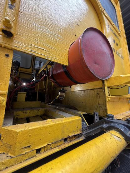 A yellow wood rear of the vehicle from underneath, with a cylindrical round red gas tank sticking out the back