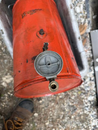 A bright red gas tank with disassembled fuel filter/gascolator assembly on top