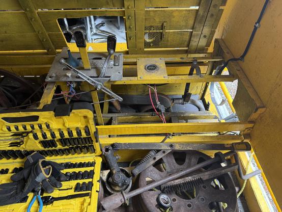 The inside of the yellow rail vehicle with the hood open, tools everywhere, and a big gap where the battery and fuel tank would usually be