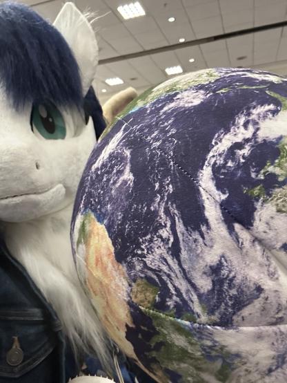 Light (unicorn fursuit) takes a selfie with a plush globe.