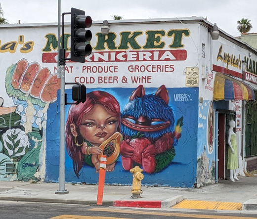 Mural of a girl and a creature hugging fruit. Might be a Lilo and Stitch riff?