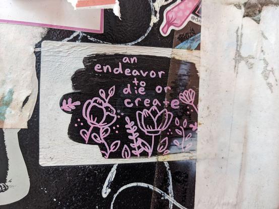 What looks to be a hand drawn sticker. It shows several pink plants over a black background. There is text that reads: An endeavor to die or create.