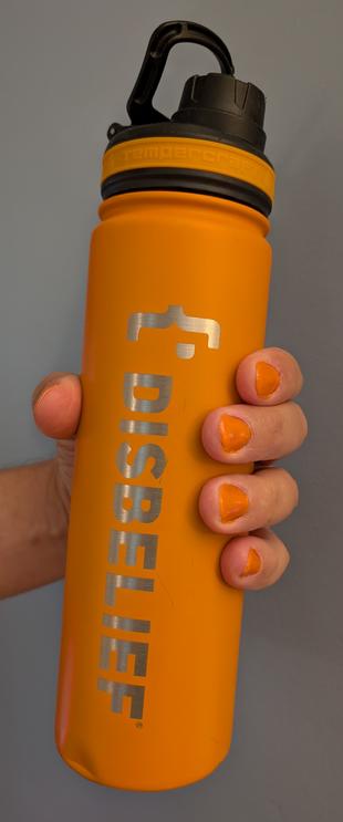 Hand with orange nails holding orange water bottle with {•DISBELIEF written on it.