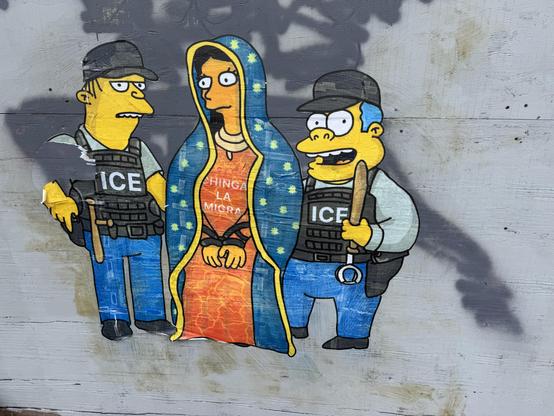 Graffiti on a wall that shows two characters from the Simpsons, Moe and Barney, dressed up as ICE agents and arresting a woman. I believe the woman is intended to be Mary, mother of Jesus, in a Spanish Catholic style, with a chapel veil and words on her dress that say "Chinga La Migra". The art was printed on paper (possibly via stencils or silkscreen) then wheatpasted on the wall.