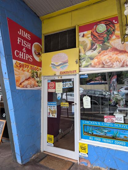Photo of the front door of a small shop with a sign saying "Jims Fish & Chips" in white text on a red background surrounded by photos of fish and chips.