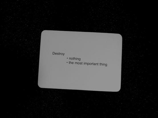 A black-and-white photo of an Oblique Strategy card. The card reads: 'Destroy -nothing -the most important thing'.