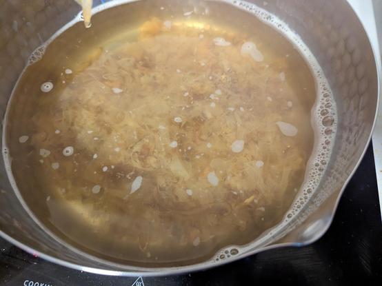 Pot of water with light brown flakes in it sink to the bottom