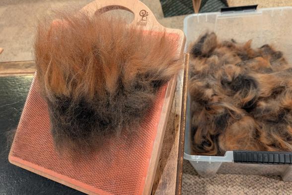 The two-tone fiber from the previous photo has been removed from the board into a bulky clump of orange tips over dark roots. It rests gently on the blending board from which it was just released.