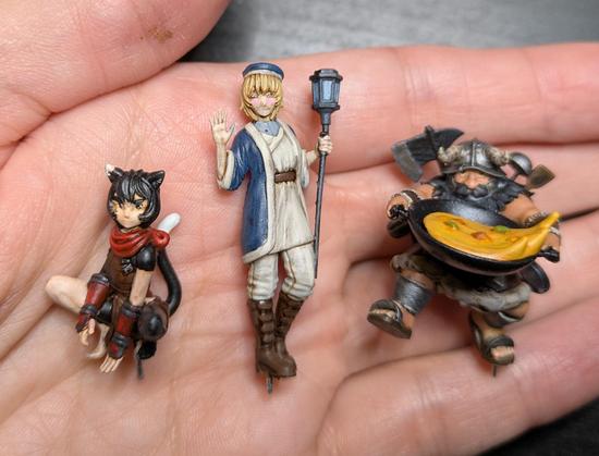 3 painted miniatures of Falin, Senshi, and Izutsumi, sitting cupped in a hand