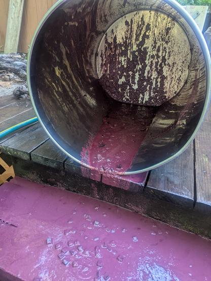A steel wine tank on its side, the remains of red wine fermentation and aging with oak cubes flow out, onto deck stairs, and presumably onto the poster's previously white socks.