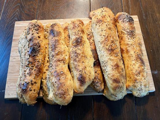 Auf einem dunklen Holztisch liegt ein Holzbrett. Darauf liegen zahlreiche frisch gebackene Seelen