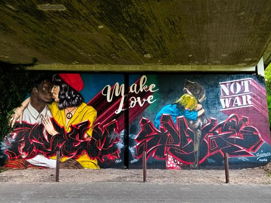 The large mural of a couple kissing and a child hugging a sitting dog plus the words "Make love not war".