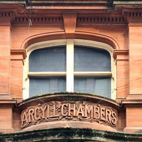 An inscribed nameplate on a small balcont in front of an arched window which reads Argyll Chambers.