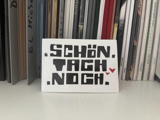 Im Vordergrund ein Sticker mit der Aufschrift SCHÖN TACH NOCH. Im Hintergrund sind viele Schallplatten zusehen.