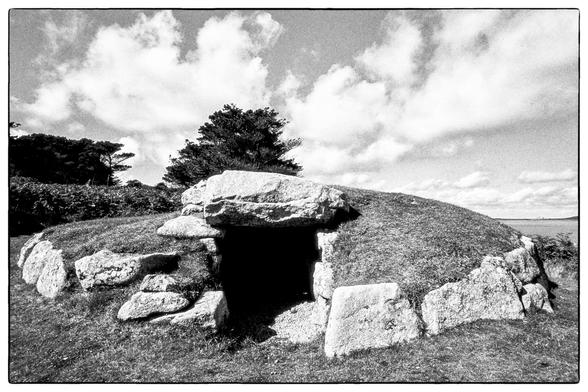 The entrance to a circular bronze age burial chamber surrounded by large stones and with a capstone above.