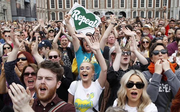 A crowd of people celebrating the referendum result. One is holding up a sign saying 'Repeal'.