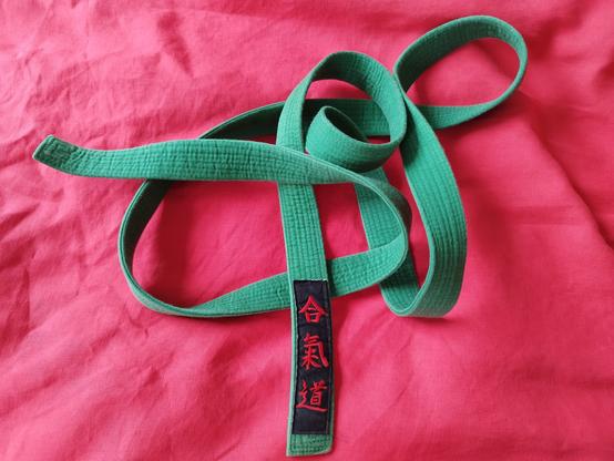 Grüner Aikido Gürtel vor rotem Hintergrund