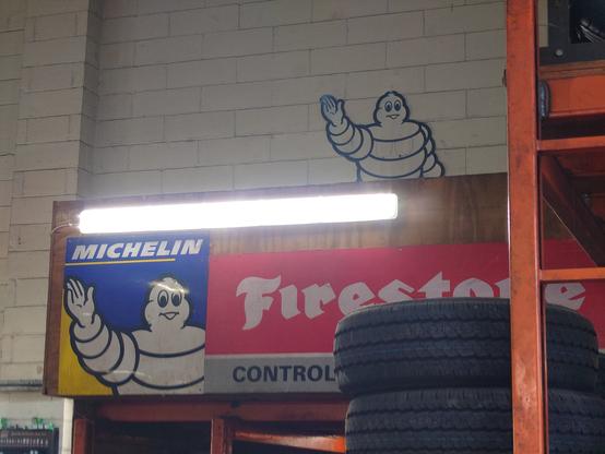 Two pictures of Bibendum (michelin man) as advertising material at a tyre garage in Mid Suffolk