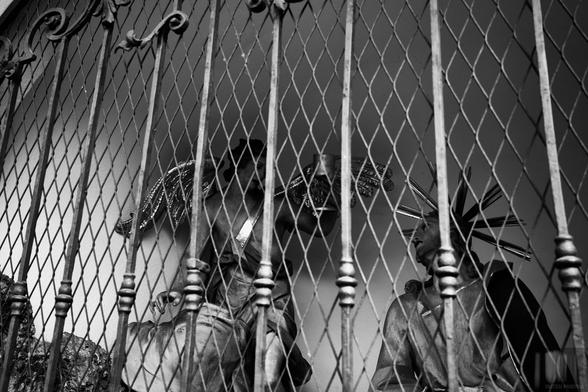 Black and white photograph of two baroque sculptures through an iron lattice in Salzburg, Austria.