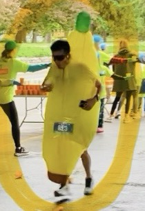 Volunteers hand out water as a runner dressed in a banana suit runs by